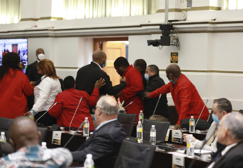 Members of the opposition, Economic Freedom Fighters (EFF) party in red, are ejected from parliament in Cape Town, South Africa, Thursday, June 9, 2022 for disrupting proceedings. South African President Cyril Ramaphosa is facing the biggest challenge to his presidency and is expected to face calls from opposition lawmakers to step down pending a criminal investigation into allegations that he tried to cover up the theft of $4 million from his game farm in the northern Limpopo province. (AP Photo/Nardus Engelbrecht)