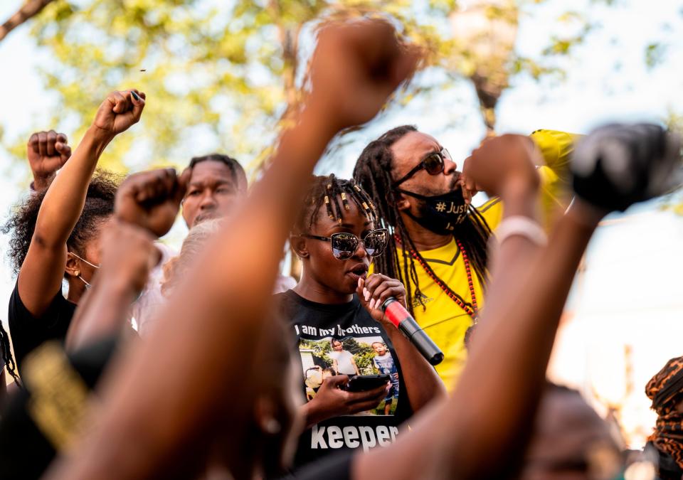 letetra wideman speaks at a rally with justin blake at her side and supporters raising their fists around her