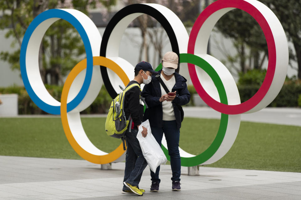 A boy looks at a cellphone after his mother took pictures of him in front of a display of the Olympic rings at the Japan Olympic Museum in Tokyo on Friday, April 2, 2021. Tokyo pitched itself as "a safe pair of hands” when it was awarded the Olympics 7 1/2 years ago. Now, nothing is certain as Tokyo's postponed Olympics hit the 100-days-to-go mark on Wednesday, April 14, 2021. (AP Photo/Hiro Komae)