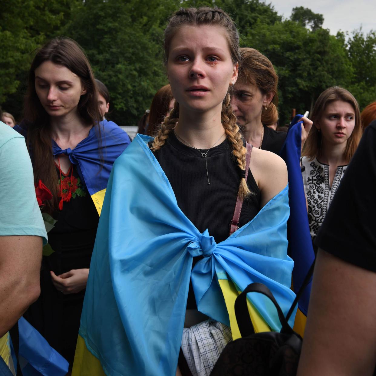 Loved ones attend a funeral ceremony for activist and soldier R. Ratushnyi , 24, who was killed while fighting in the Kharkiv region during the Russian invasion, at Baikove Cemetery in Kyiv, Ukraine, on June 18, 2022. Ratushnyi has become a symbol of revolution and mourners came wrapped in the Ukrainian flag, leaving flowers and sorrow at his gravesite.