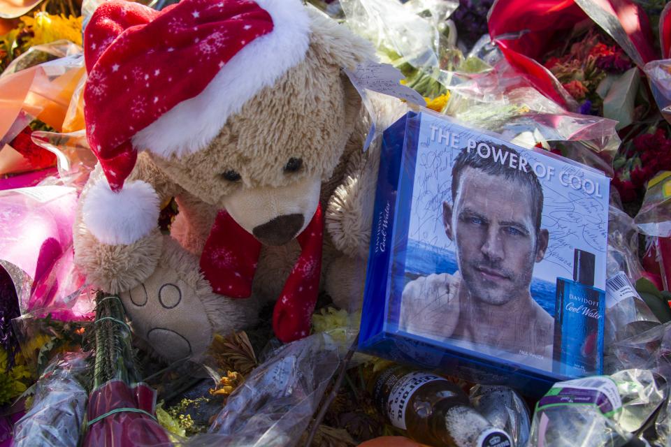 Flowers and messages are left at a memorial rally and car cruise in Valencia, Calif., Sunday, Dec. 8, 2013 to remember actor Paul Walker and his friend Roger Rodas, who died in a fiery car crash last Saturday. (AP Photo/Ringo H.W. Chiu)