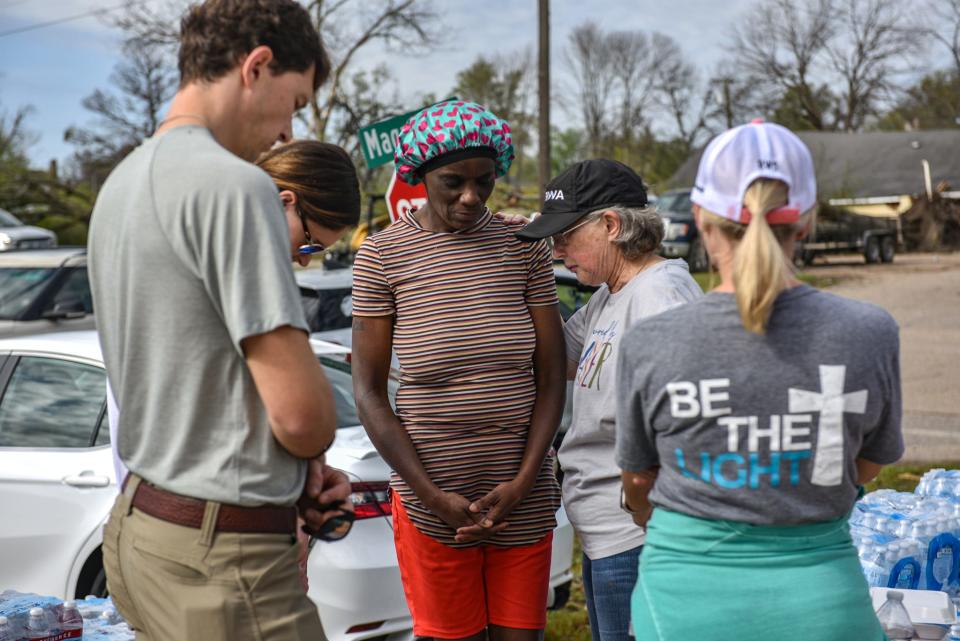 Rushonda Atlas, center, prays with volunteers from First Baptist Church of Flora resident in Rolling Fork on Sunday. Some Rolling Fork churches had makeshift services without a standing sanctuary.