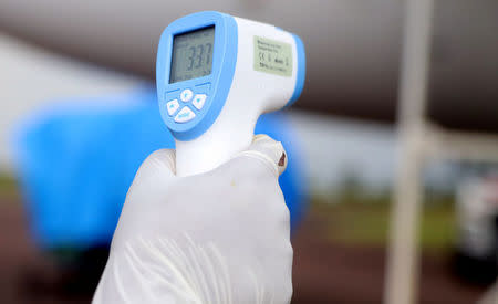 A Congolese health worker checks the temperature of passengers disembarking from a Congo Airways plane in Mbandaka, Democratic Republic of Congo May 19, 2018. REUTERS/Kenny Katombe