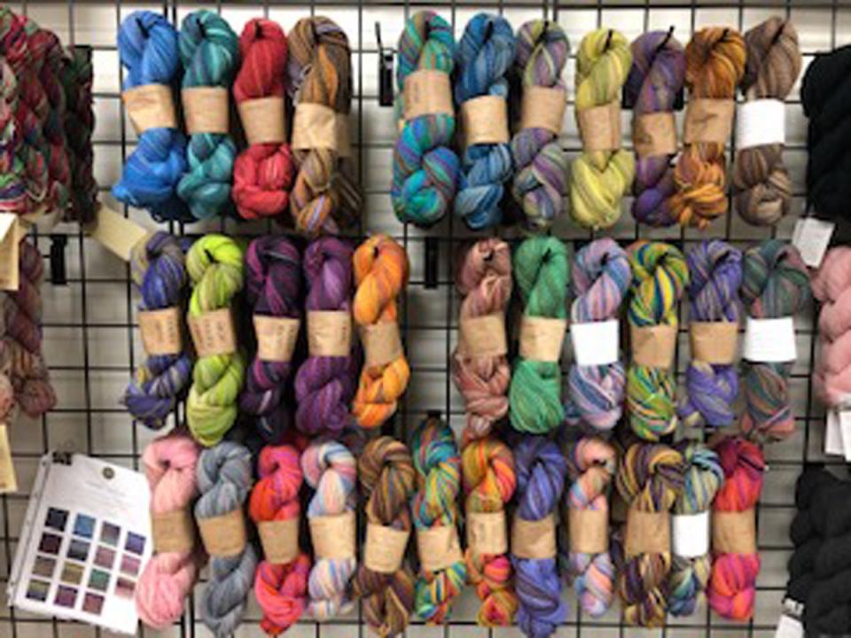 Multi-colored yarn skeins are seen hanging from a display at the Bird's Nest in downtown Macomb.