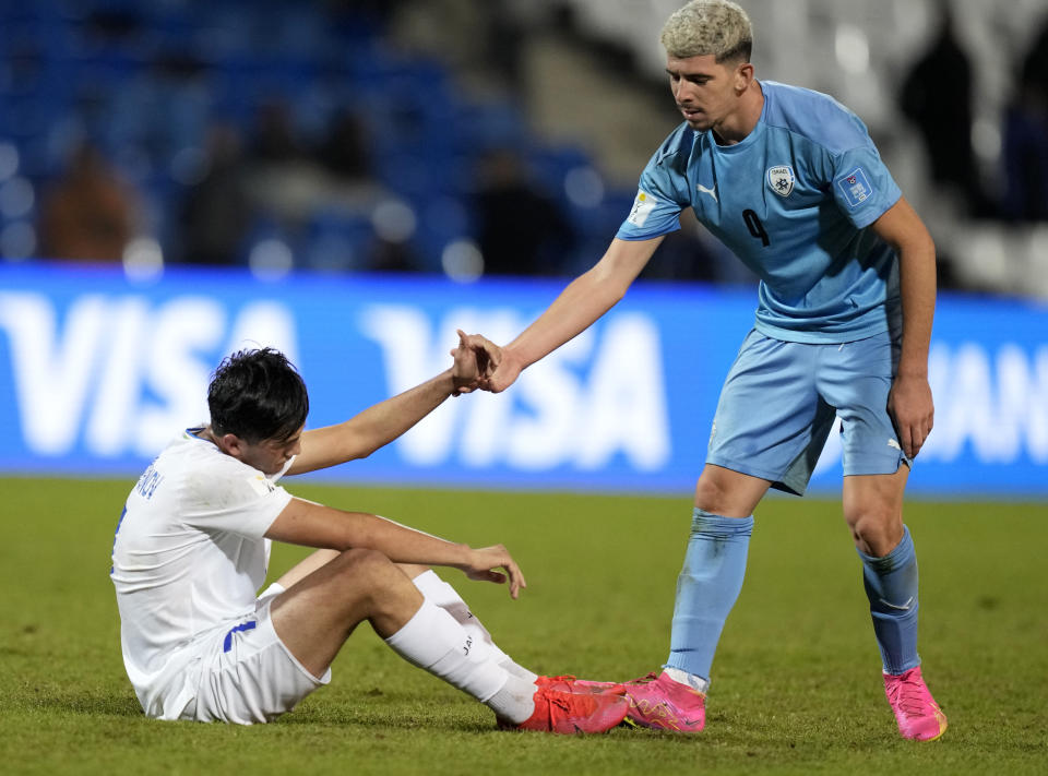 Israel's Dor Turgeman, right, helps Uzbekistan's Pulatkhuja Kholdorkhonov up after a FIFA U-20 World Cup round of 16 soccer match were Uzbekistan was eliminated, at the Malvinas Argentinas stadium in Mendoza, Argentina, Tuesday, May 30, 2023. (AP Photo/Natacha Pisarenko)