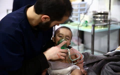 A man seen administering breathing apparatus to a child in hospital in the besieged town of Douma, Eastern Ghouta - Credit: BASSAM KHABIEH/ REUTERS