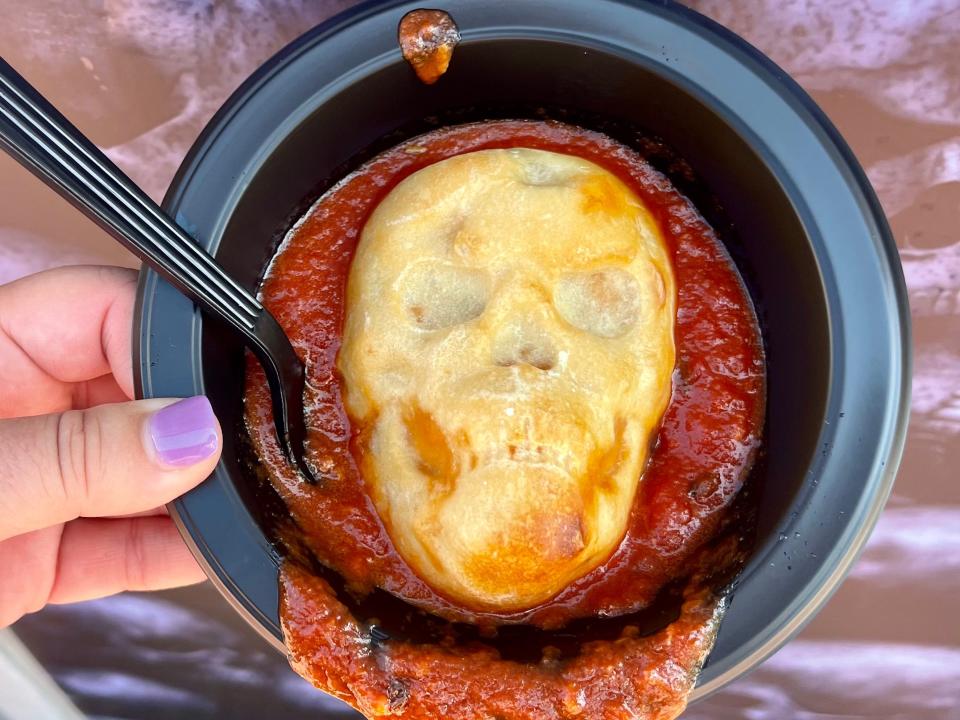 hand holding bowl with skull-shaped pizza from halloween horror nights