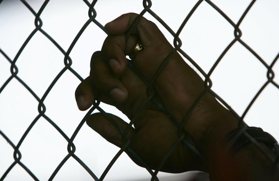 An inmate holds onto a fence during the Angola Prison Rodeo at the Louisiana State Penitentiary April 23, 2006 in Angola, Louisiana. (Photo by Mario Tama/Getty Images)