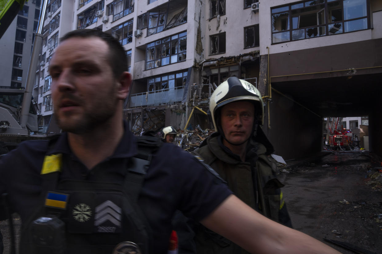 Policemen and firefighters work at the scene at a residential building following explosions, in Kyiv, Ukraine, Sunday, June 26, 2022. Several explosions rocked the west of the Ukrainian capital in the early hours of Sunday morning, with at least two residential buildings struck, according to Kyiv mayor Vitali Klitschko. (AP Photo/Nariman El-Mofty)