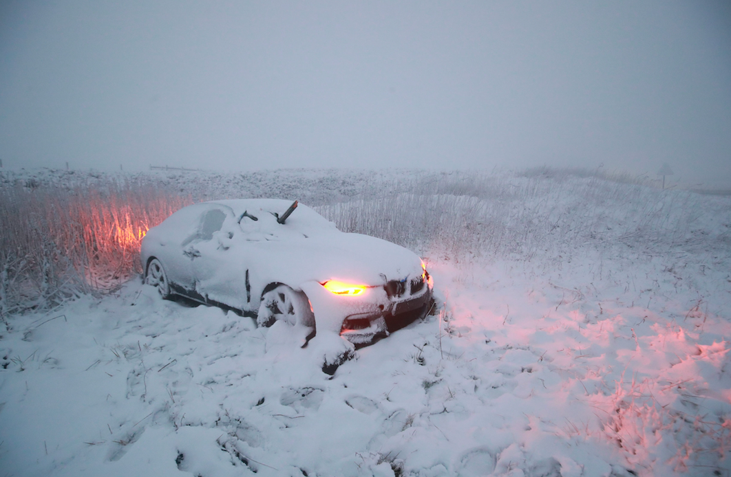 <em>A crashed car, with an object protruding through the windscreen, sits abandoned on the A628 in the Peak District, as a blast of snow hits the north of England (PA)</em>