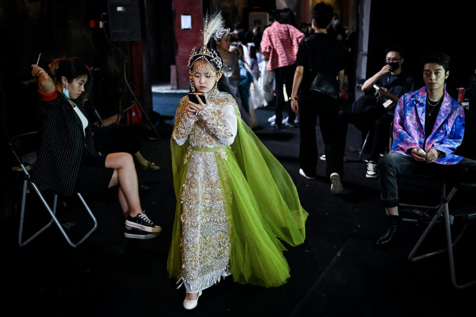 A young model looks at her mobile phone as she waits backstage during the China Fashion Week in Beijing on September 3, 2021. (Wang Zhao / AFP via Getty Images)