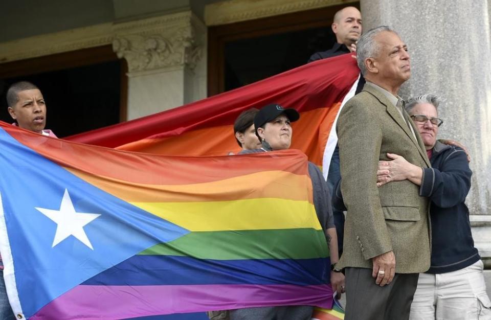 FILE - Former Hartford Mayor Pedro Segarra and Shawn Lang, right, of Hartford, embrace after Segarra spoke Sunday, June 12, 2016, during a vigil organized by the state's Muslim and lesbian, gay, bisexual and transgender communities on the steps of the state Capitol building in reaction to the mass shooting in Orlando, Fla, Holding gay pride flags behind Segarra and Lang are from left, Fioroella Hidalgo, Becky Muniz, wearing hat, Stephen Vetter and Charlie Ortiz. Lang, a longtime Connecticut activist for people living with HIV and AIDS, as well as those impacted by opioid addiction and domestic abuse, died Sunday, Oct. 17, 2021. She was 65.