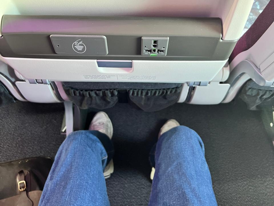 A passenger shows the adequate leg room in the economy seats on a Qatar Airbus A350