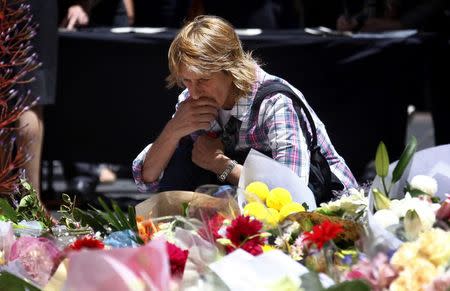 A woman reacts after placing a floral tribute amongst thousands of others that have been placed near the cafe where hostages were held for over 16-hours, in central Sydney December 16, 2014. REUTERS/David Gray