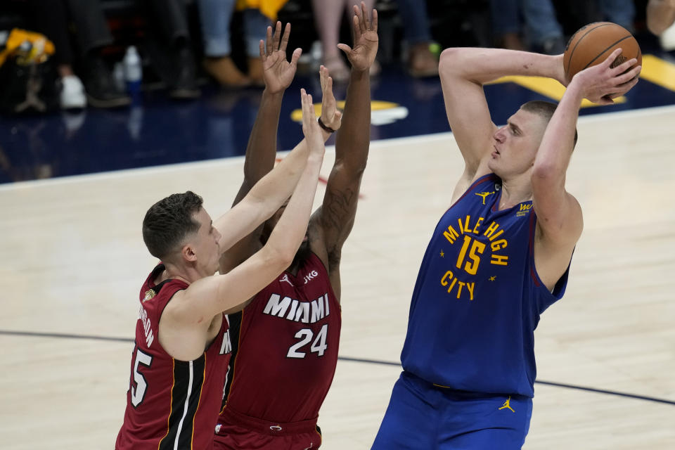 Denver Nuggets center Nikola Jokic, right, shoots over Miami Heat forwards Duncan Robinson, left, and Haywood Highsmith during the first half of Game 1 of basketball's NBA Finals, Thursday, June 1, 2023, in Denver. (AP Photo/David Zalubowski)