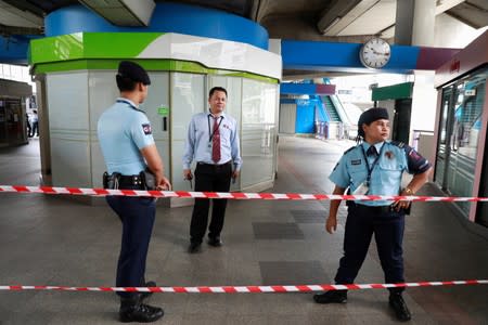 Security officers stand at the site of a small explosion at a BTS train station in Bangkok, Thailand,