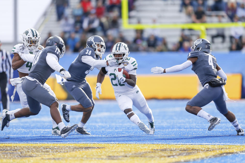 Ohio running back O'Shaan Allison, center, runs with the ball as Nevada defensive back Christian Swint (38) reaches across his face guard and Nevada defensive backs Jordan Lee, left, and EJ Muhammad, right, close in for the tackle in the first half of the Famous Idaho Potato Bowl NCAA college football game Friday, Jan. 3, 2020, in Boise, Idaho. (AP Photo/Steve Conner)
