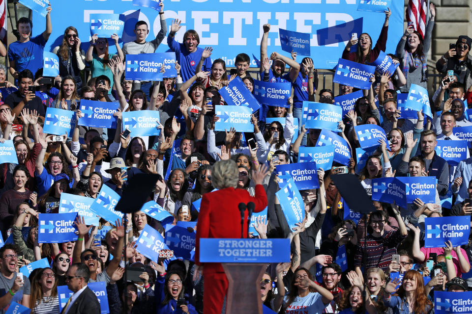 FILE - In this Nov. 7, 2016, file photo, Democratic presidential candidate Hillary Clinton waves to students standing behind her before speaking at a rally in front of the Cathedral of Learning on the University of Pittsburgh campus. The notion of “blue states” and “red states” in the United States emerged during the aftermath of the contested 2000 election when TV networks used frequent on-air maps to show the breakdown between states going for Texas Gov. George W. Bush and Vice President Al Gore. Talk of red and blue states and even “Red America” and “Blue America” has continued ever since. (AP Photo/Gene J. Puskar, File)