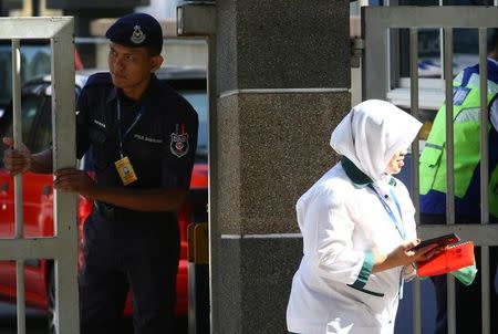 A police officer looks on as a hospital staff walks past outside the morgue at Kuala Lumpur General Hospital where Kim Jong Nam's body is held for autopsy in Malaysia, February 17, 2017. REUTERS/Athit Perawongmetha