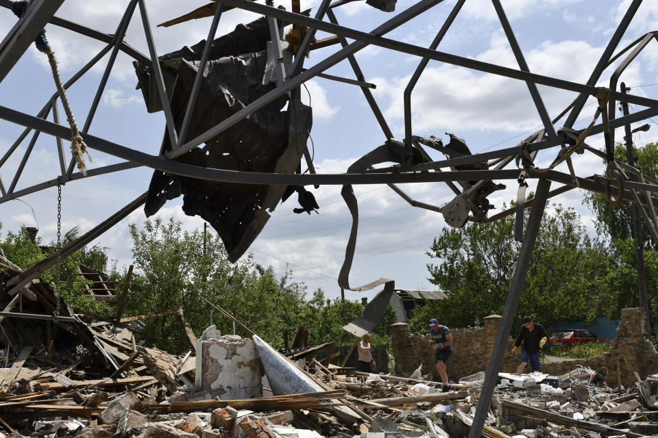 Varias personas limpian una zona donde un edificio fue destruido por misiles, el miércoles 1 de junio de 2022, en Sloviansk, Ucrania. (AP Foto/Andriy Andriyenko)