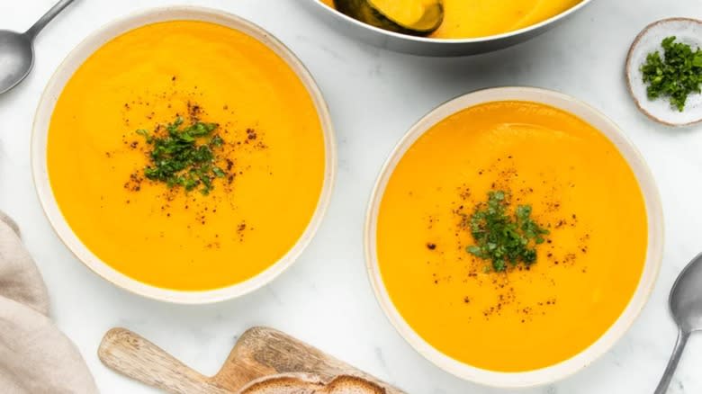 Bowls of carrot soup with parsley garnish