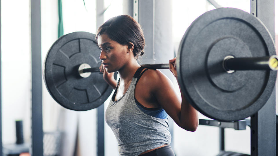 Cropped shot of a young woman working out with a barbell at the gym