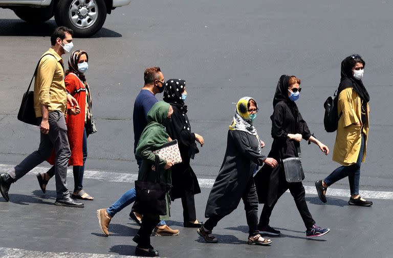 Los iraníes, enmascarados debido a la pandemia de coronavirus, cruzan una calle en la capital, Teherán