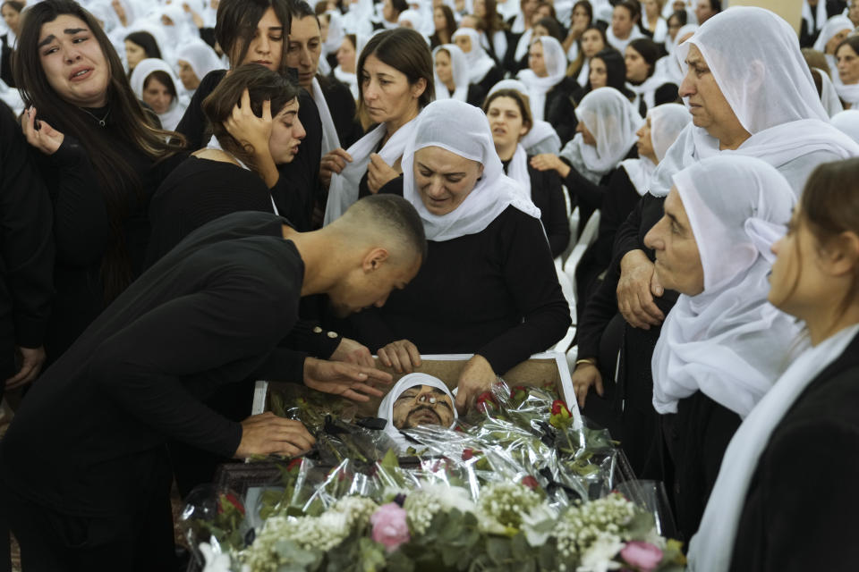 Members of the Israeli Druze minority mourn around the body of Tiran Fero, 17, during his funeral in Daliyat al-Carmel, Israel, Thursday, Nov. 24, 2022. Fero's body, which was taken by Palestinian militants from a West Bank hospital where he was seeking treatment after a car accident, was returned to his family on Thursday. (AP Photo/Mahmoud Illean)