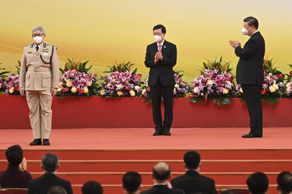 China's President Xi Jinping, right, and Hong Kong's new Chief Executive John Lee, center, clap as Hong Kong's Director of Immigration Au Ka-wang is sworn in during a ceremony to inaugurate the city's new government in Hong Kong Friday, July 1, 2022, on the 25th anniversary of the city's handover from Britain to China. (Selim Chtayti/Pool Photo via AP)