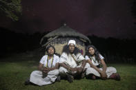 Arhuaco Indigenous siblings, twins Irene, left, Alba, 16, and Sebastian, 30, center, sit in front of their home in Nabusimake on the Sierra Nevada de Santa Marta, Colombia, Tuesday, Jan. 17, 2023. The twins attend school and during their off time they help with the family´s sheep. (AP Photo/Ivan Valencia)