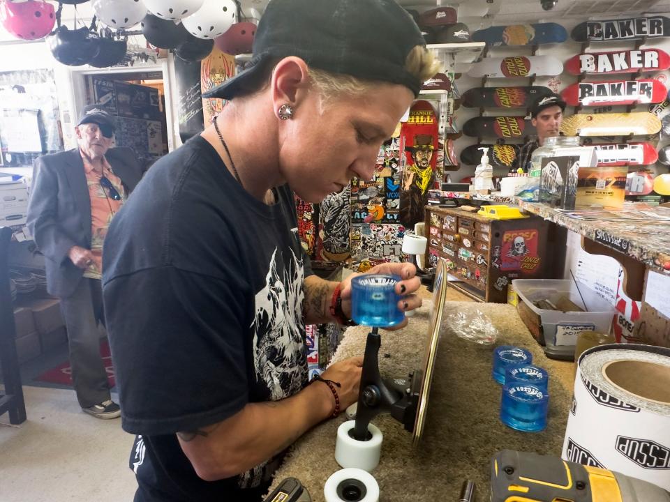 Brad Spann, owner of Five Points Skate Shop in Ventura, from left, and his employee Udo Lingmann, and his son Tyler Spann, help out a customer with some wheels on Thursday.