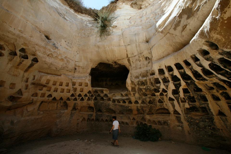 A photo of a child standing in the center of a columbarium in the foothills near an ancient city.