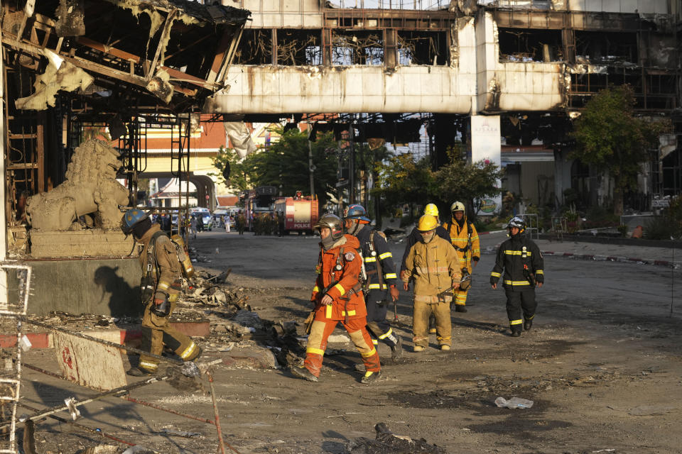 Cambodian and Thai rescue experts walk through a ruined building for a searching operation at the scene of a massive fire at a Cambodian hotel casino in Poipet, west of Phnom Penh, Cambodia, Friday, Dec. 30, 2022. The fire at the Grand Diamond City casino and hotel Thursday injured over 60 people and killed more than a dozen, a number that officials warned would rise after the search for bodies resumes Friday. (AP Photo/Heng Sinith)