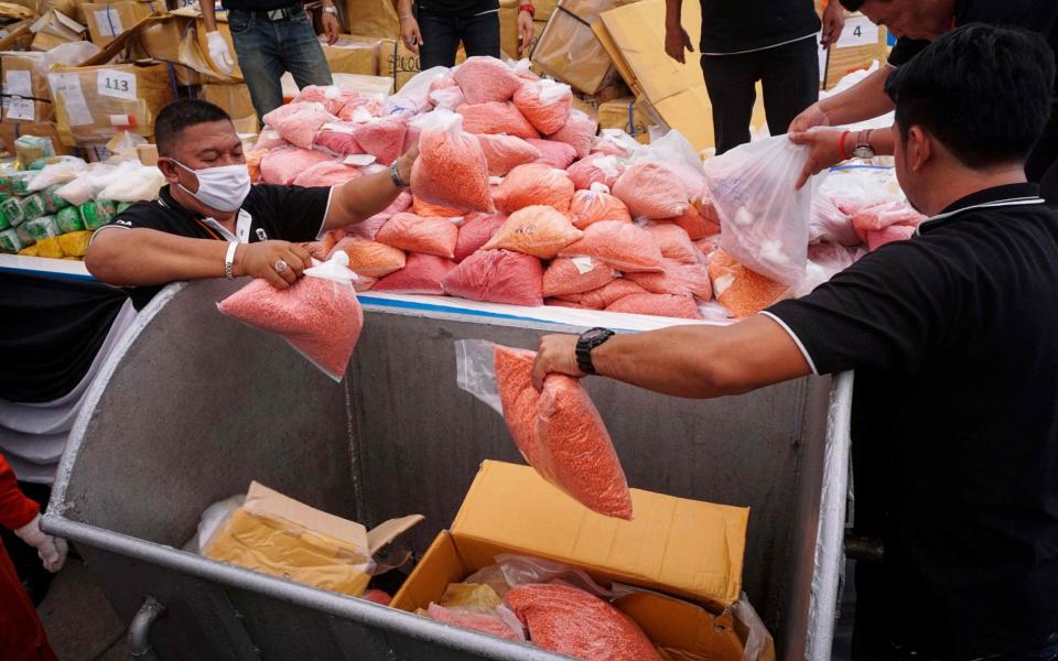 Bags of methamphetamines are put into a vat before their incineration by the Thai Government  - Credit: LILLIAN SUWANRUMPHA/AFP