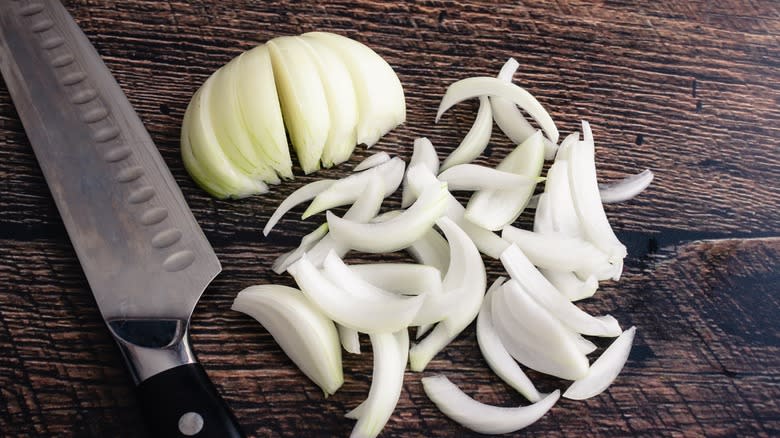 Sliced onions with knife on wood