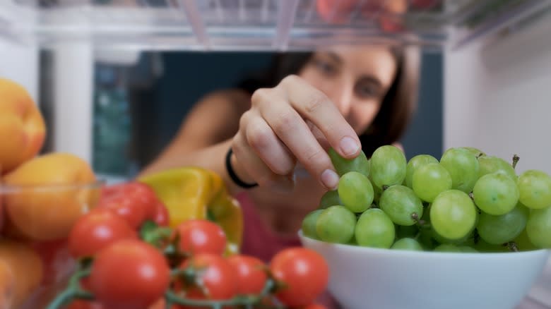 Woman grabbing grapes from fridge