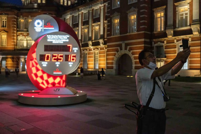 Un hombre toma una foto frente al reloj de cuenta regresiva para los Juegos Olímpicos de Tokio 2020, mostrando 7 días y 25 minutos para la ceremonia de apertura, en las afueras de la estación de Tokio.
