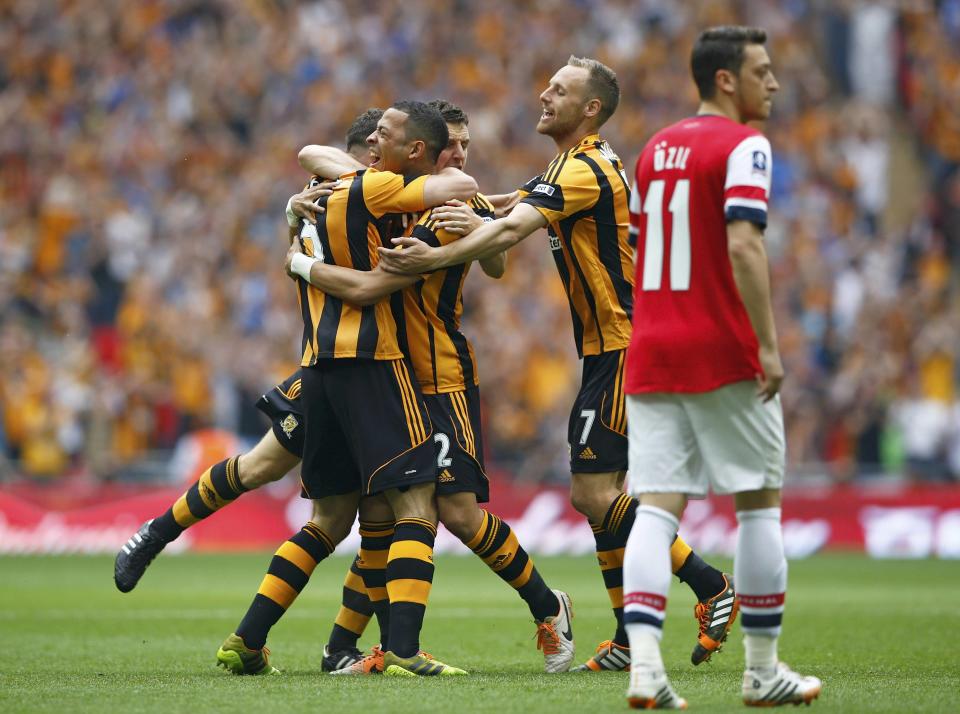 Hull City players celebrate with their team mate James Chester (L) after he scored his team's first goal, as Arsenal's Mesut Ozil (R) reacts, during their FA Cup final soccer match at Wembley Stadium in London, May 17, 2014. REUTERS/Darren Staples (BRITAIN - Tags: SPORT SOCCER)