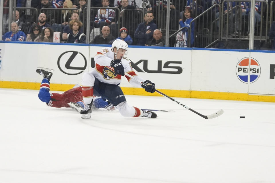 Florida Panthers center Anton Lundell, right, shoots at an empty net ahead of New York Rangers defenseman Adam Fox, left, during the third period of an NHL hockey game on Monday, March 4, 2024, in New York. (AP Photo/Peter K. Afriyie)