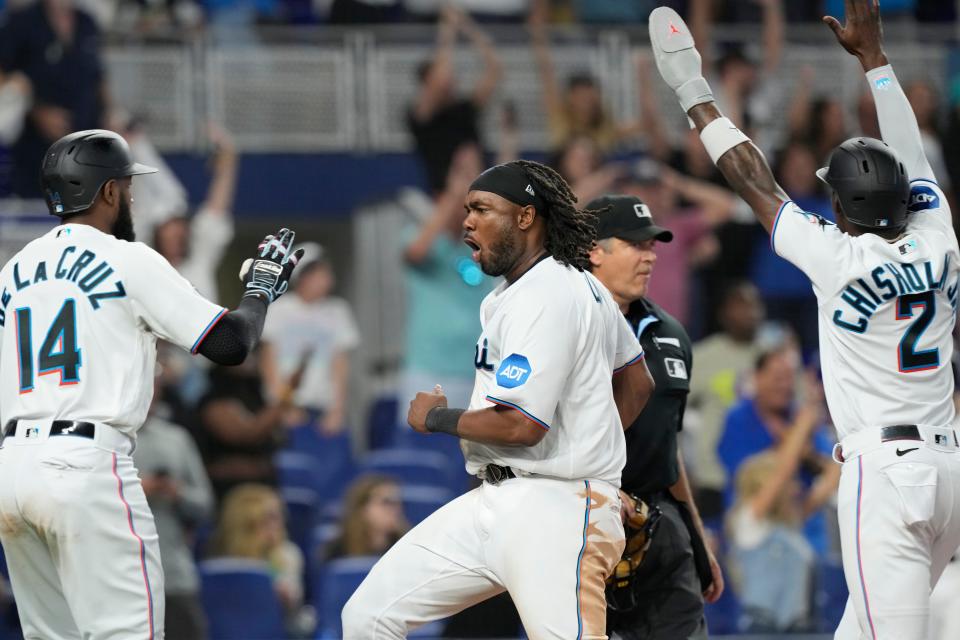 Miami Marlins' Josh Bell, center, scores on a hit by Luis Arraez to tie the game during the ninth inning of a baseball game against the New York Yankees, Sunday, Aug. 13, 2023, in Miami. The Marlins defeated the Yankees 8-7. (AP Photo/Marta Lavandier)