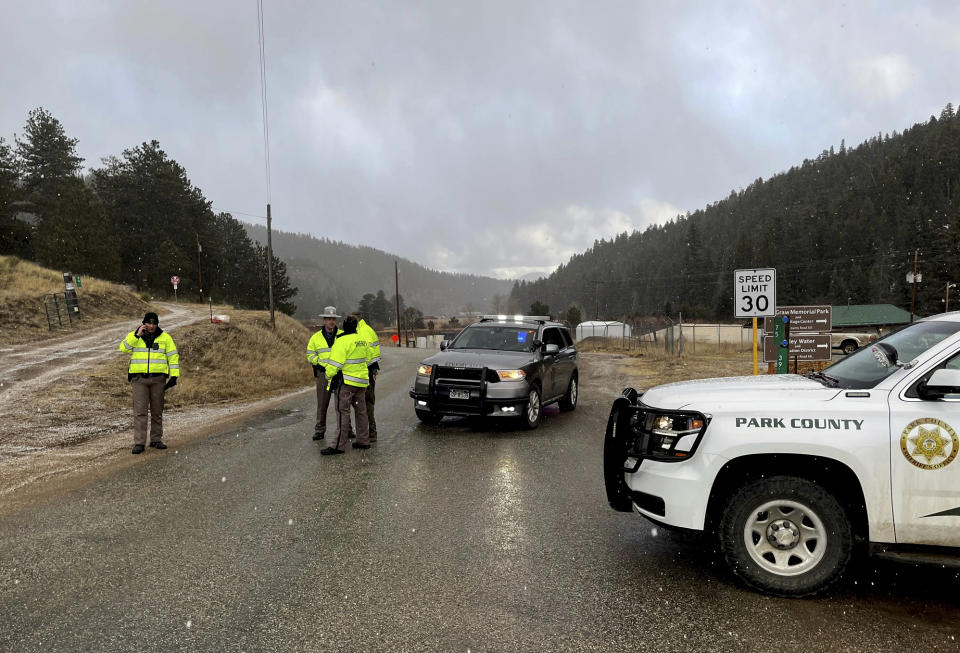 Sheriff deputies block a road in the town of Bailey, Colo., where authorities found an abandoned car that belonged to the suspect in a shooting of two administrators at a Denver high school Wednesday, March 22, 2023. (AP Photo/Thomas Peipert)