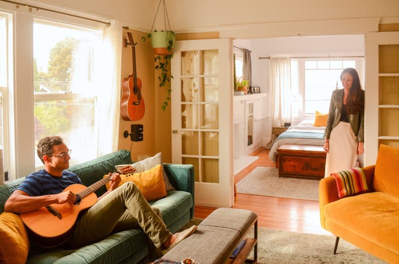 Dweller plays acoustic guitar in living area.