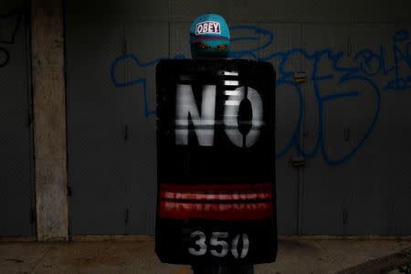 A demonstrator holding a rudimentary shield that reads "No. Dictatorship. 350", poses for a picture before a rally against Venezuelan President Nicolas Maduro's government in Caracas, Venezuela, June 17, 2017. He said: "I protest for the freedom of the country." REUTERS/Carlos Garcia Rawlins