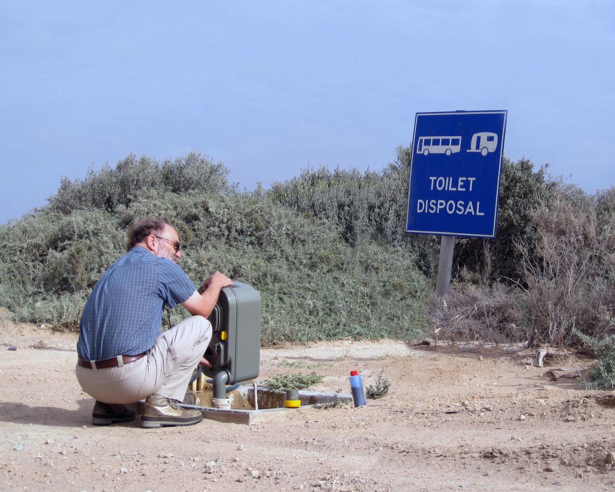 man disposing toilet tank at rv trailer disposal