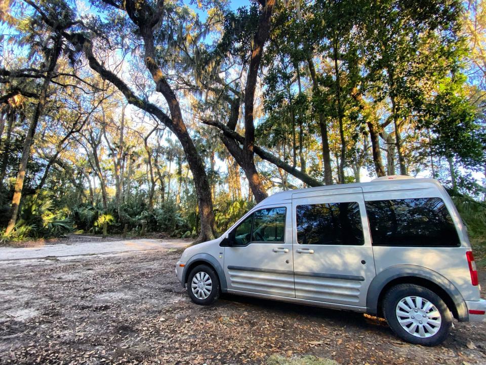 abbey's van sitting in a tree-filled forest over gravel road