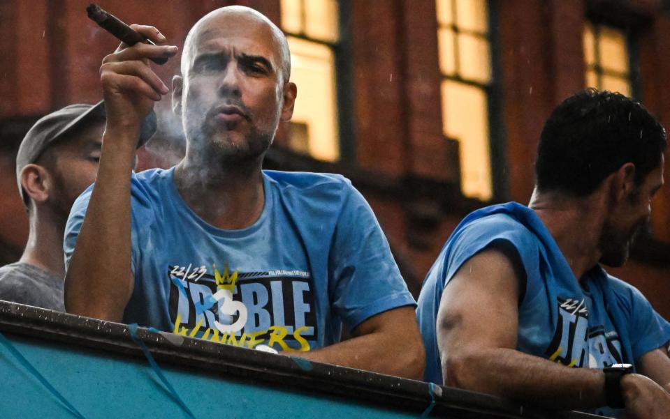 Pep Guardiola smokes a cigar while celebrating Man City's treble success