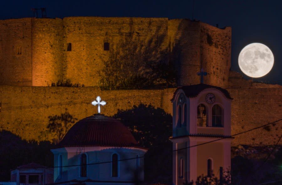 The supermoon rises behind the Chlemoutsi medival castle in Kyllini, Peloponnese, Greece, Wednesday, Aug. 30, 2023. The cosmic curtain rose Wednesday night with the second full moon of the month, the reason it is considered blue. (AP Photo/Petros Giannakouris)