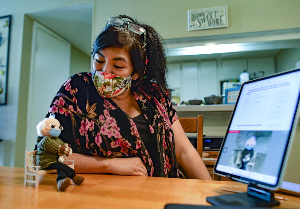 Tobey King speaks to her crochet Bernie Sanders doll as the bidding continues on eBay on Tuesday, Jan. 26, 2021 in Corpus Christi, Texas. The doll sold for $20,300, and all of the proceeds are being donated to Meals on Wheels. (Billy Calzada/The San Antonio Express-News via AP)