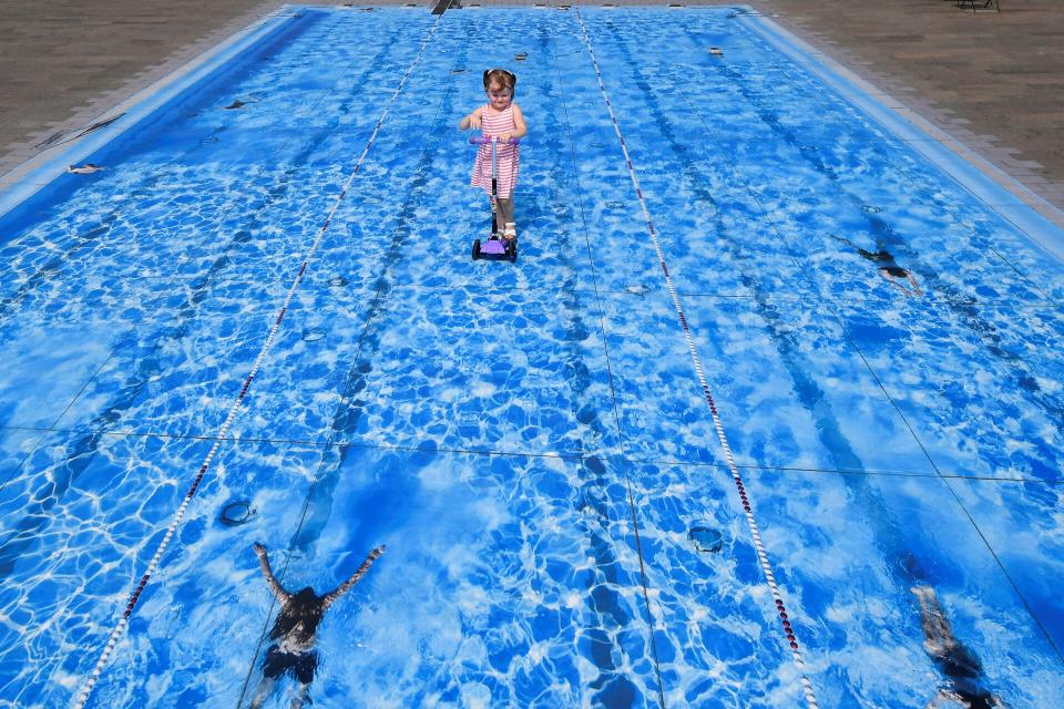 Eliza, 3, scoots over a piece of temporary floor art depicting a swimming pool, amid the coronavirus disease (COVID-19) outbreak, in London, Britain August 12, 2020.