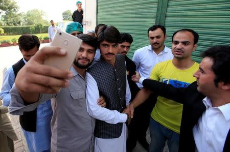 Arshad Khan (C), formerly a chai wala (tea seller) by profession, posses for a selfie with fans after doing a television interview in Islamabad, Pakistan October 20, 2016. REUTERS/Faisal Mahmood